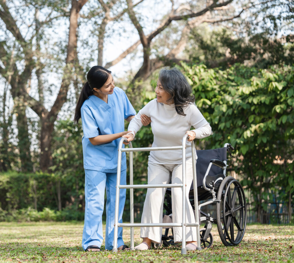 Elderly Woman with Caregiver Assisting in Rehabilitation Outdoors Using a Walker