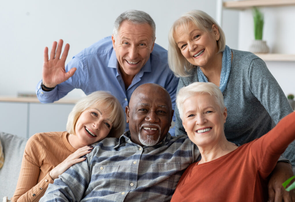 Happy elderly people taking selfie together, home interior
