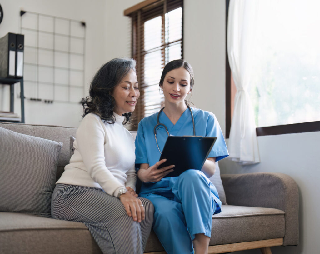 Nurse consulting with senior woman on sofa in home